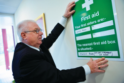 An image of first aid poster with Health & Safety representative putting it up