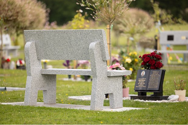 A granite memorial bench with flowers