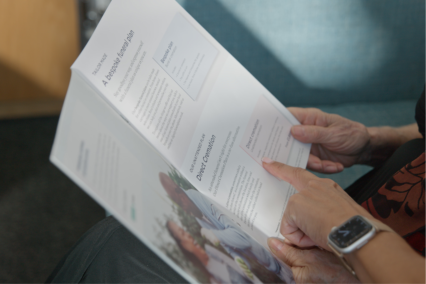 Hands holding an open funeral plan brochure, with a panel headed Direct Cremation.