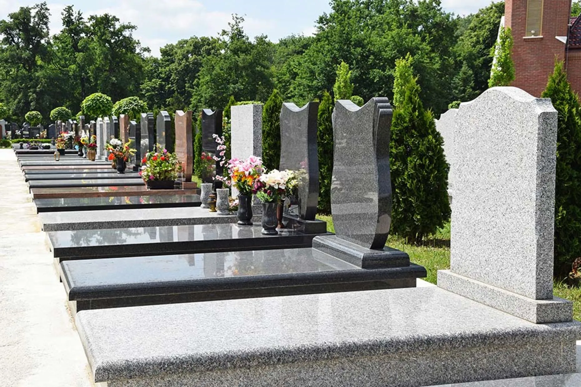 Rows of headstones and memorials in a well-kept cemetery.